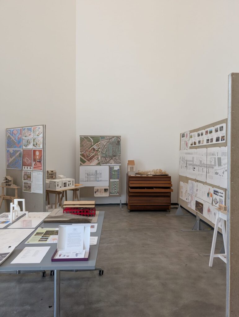Gallery space at the MAC shows many architectural drawings and site photographs for a housing development