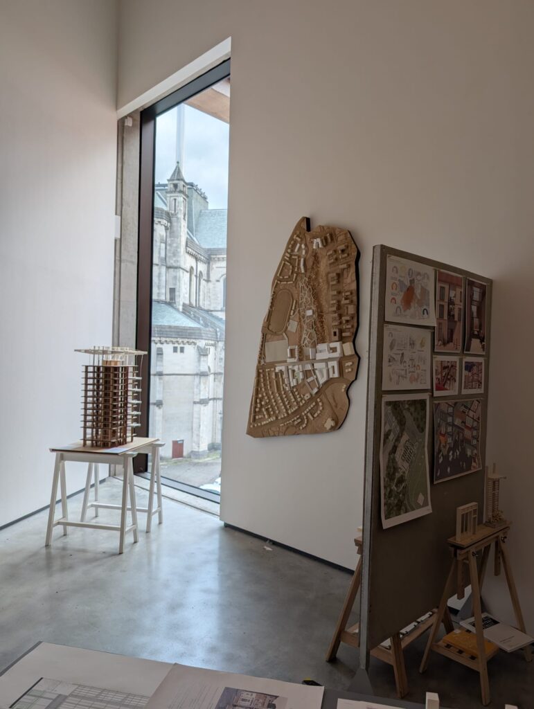 Gallery space at the MAC shows a 3D masterplan for housing development, an easel with architectural drawings and site photographs and a 3D building model.